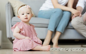 Маленькая девочка в розовом платье сидит на полу