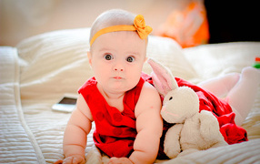 Маленькая девочка в красном платье с игрушкой 