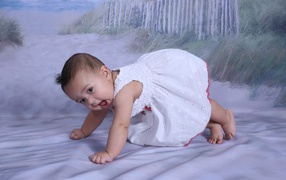 Маленькая девочка в белом платье на кровати 