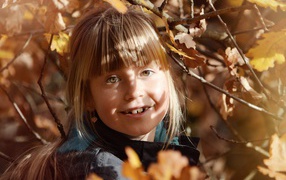 Маленькая девочка в ветках дерева осенью 