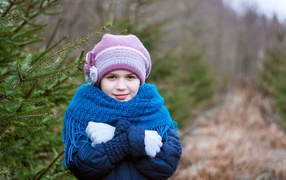 Маленькая девочка в теплой одежде у ели