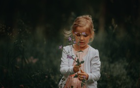 Маленькая девочка с полевым цветком в руке