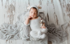 Little sleeping nursing baby in white suit