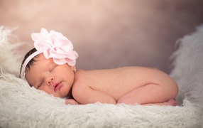 Новорожденная девочка с большим цветком на голове 
