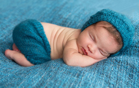 Спящий грудной ребенок лежит на голубом покрывале 