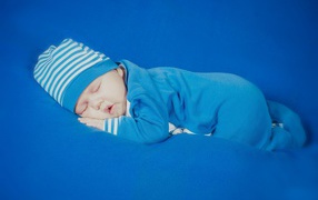 Спящий грудной ребенок в голубом костюме 