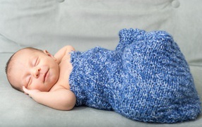 Маленький грудной ребенок в синем вязаном покрывале 
