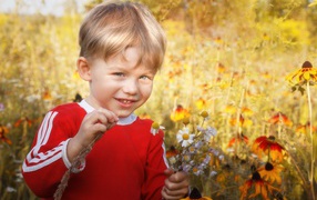Улыбающийся голубоглазый мальчик с полевыми цветами 