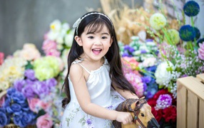 Smiling little asian girl riding a horse