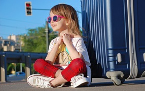 Улыбающаяся маленькая девочка в очках с чемоданом
