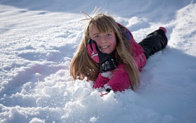 Smiling little girl lying in the snow