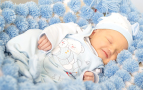 Улыбающийся грудной ребенок спит на голубом покрывале