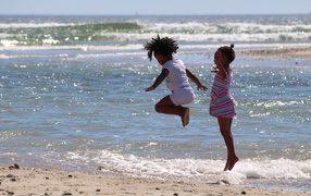 Две маленькие девочки играют на морском берегу
