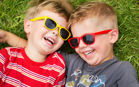 Two smiling boys in glasses on green grass