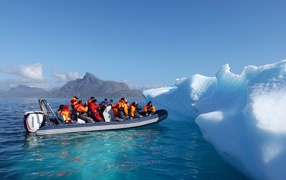 Группа туристов на лодке у айсберга