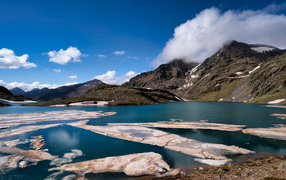 Лед на озере у гор под голубым небом 