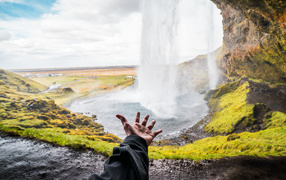 Рука тянется к водопаду Сельяландсфосс, Исландия