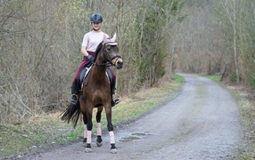 Молодая девушка катается на лошади 