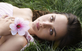 Актриса Ана де Армас лежит на зеленой траве с цветком