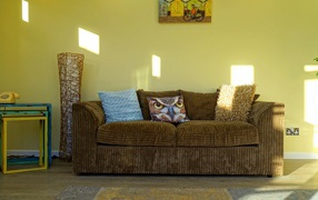 Большой старый диван в комнате с желтыми стенами