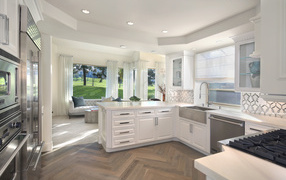 Белый кухонный гарнитур в комнате с большим окном