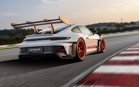 Серебристый спортивный автомобиль Porsche 911 GT3 RS Weissach Package 2023 года на трассе