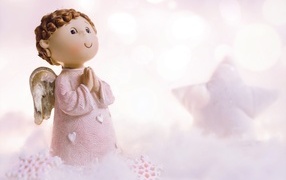 Маленькая статуэтка ангела стоит на снегу