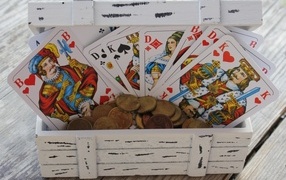 A deck of cards and coins in a wooden box