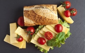 Cheese with loaf and tomatoes on the table
