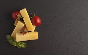 Cheese with tomatoes and basil leaves on a gray table
