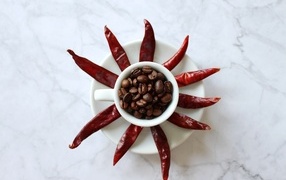 Кофейные зерна в чашке на тарелке с красным перцем
