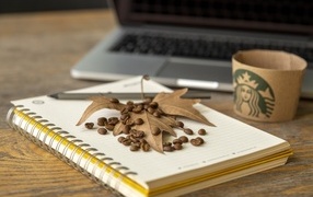 Coffee beans with leaf and notepad on table