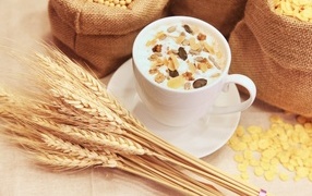 Cup of milk with cereals on a table with wheat