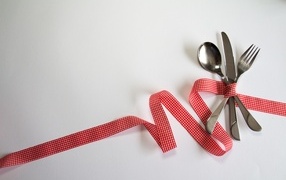 Cutlery tied with ribbon on gray background