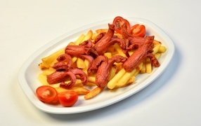 French fries on a plate with tomatoes and sausages