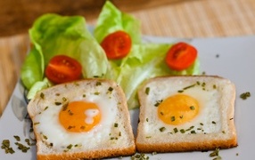 Яичница с хлебом, помидорами и листьями салата на завтрак