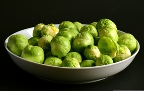 Green brussels sprouts in a plate on a black background