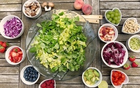 Green salad on the table with berries and vegetables