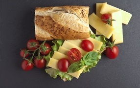 Long loaf with cheese and tomatoes on a gray background