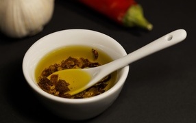 Olive oil in a plate on the table with pepper and garlic