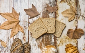 Pieces of bread with leaves on a wooden table