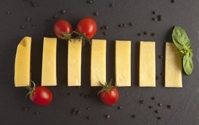 Кусочки сыра с помидорами на сером столе