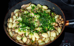 Potatoes with champignons and green onions in a frying pan