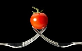 Red tomato with forks on black background