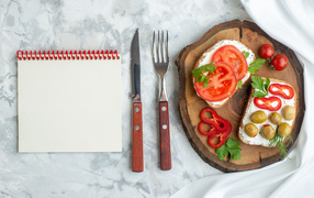 Sandwiches on the table with cutlery and notepad