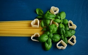 Spaghetti on blue background with basil leaves
