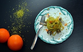 Спагетти с морепродуктами на столе с апельсинами