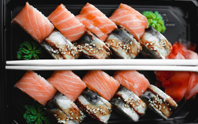 Sushi with fish on a black plate with chopsticks