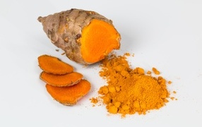 Turmeric root with powder on gray background