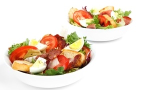 Two bowls of delicious salad on a white background